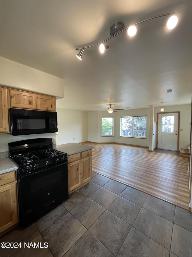 kitchen with dark tile patterned flooring, black appliances, and a wealth of natural light