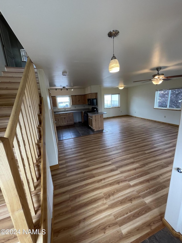 unfurnished living room with sink, dark hardwood / wood-style floors, and ceiling fan