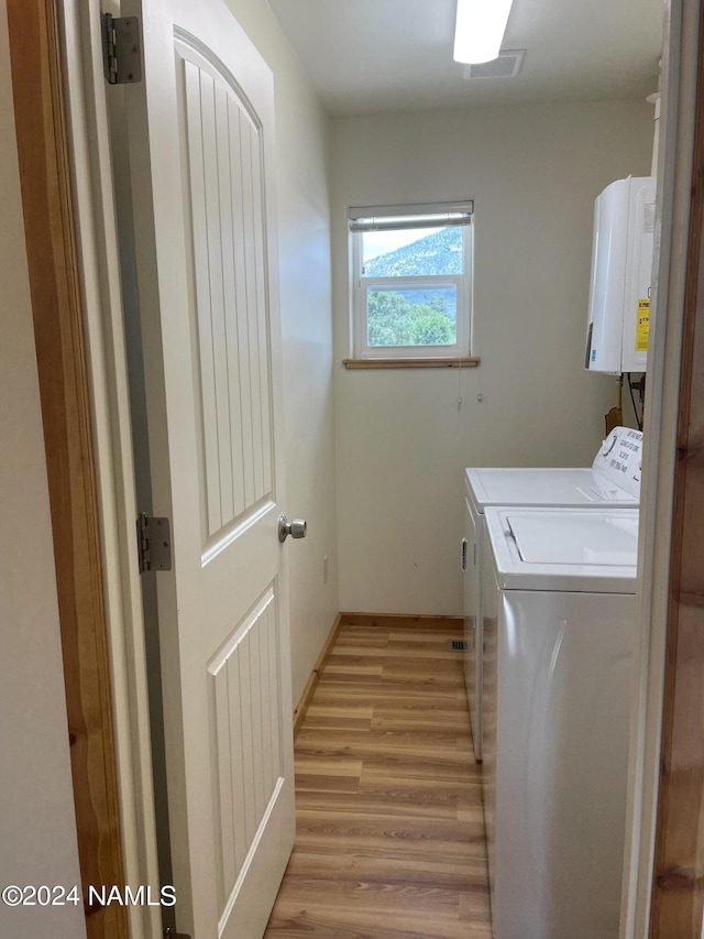 laundry room with washer and dryer, light hardwood / wood-style flooring, and water heater