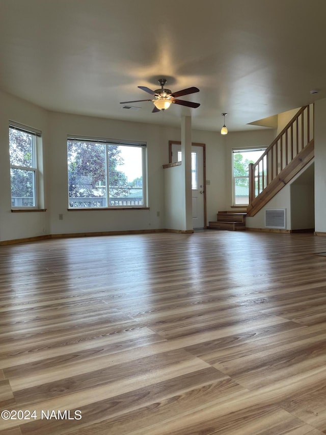 unfurnished living room featuring hardwood / wood-style floors, plenty of natural light, and ceiling fan