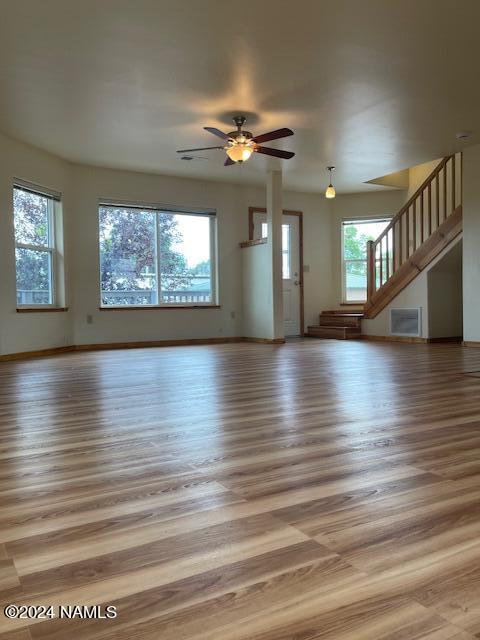 unfurnished living room with ceiling fan, hardwood / wood-style floors, and plenty of natural light