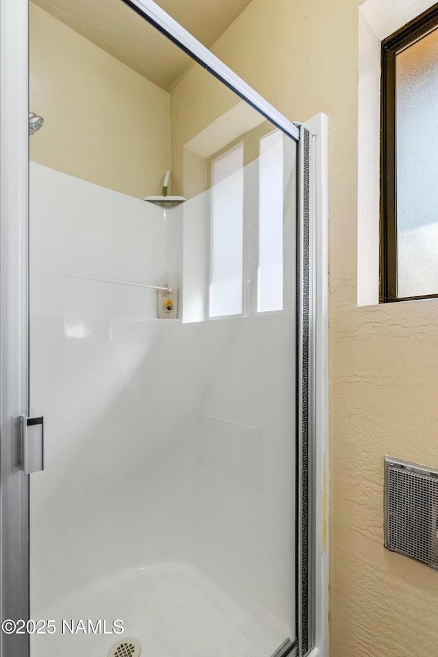 bathroom featuring visible vents, a healthy amount of sunlight, a stall shower, and a textured wall