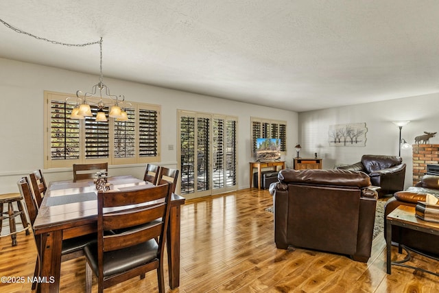 dining room featuring a textured ceiling, an inviting chandelier, and wood finished floors