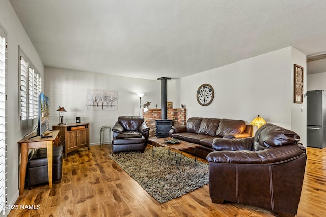 living area with a wood stove and wood finished floors