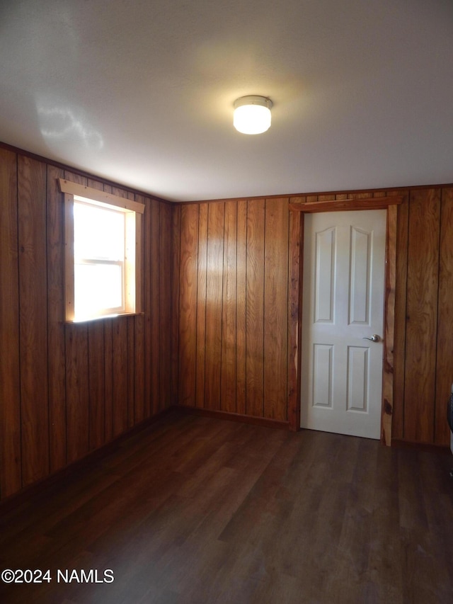 spare room featuring wood walls and dark wood-type flooring