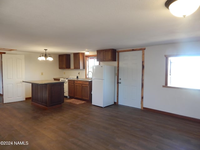 kitchen with white appliances, sink, a kitchen island, pendant lighting, and dark hardwood / wood-style flooring