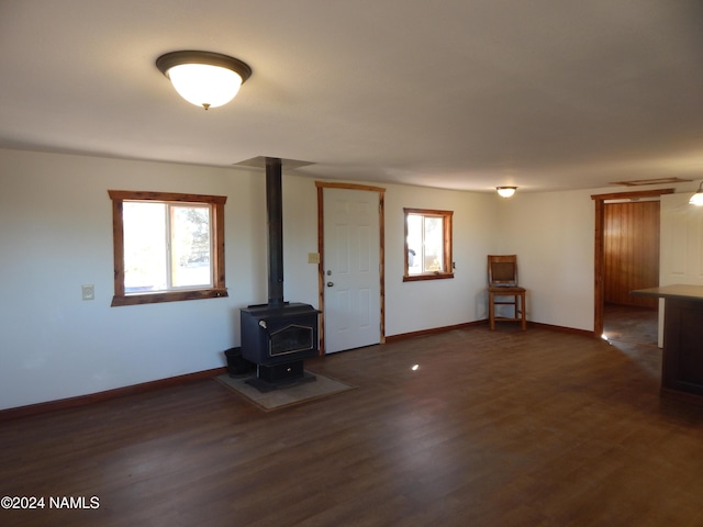 unfurnished living room featuring dark wood-type flooring and a wood stove