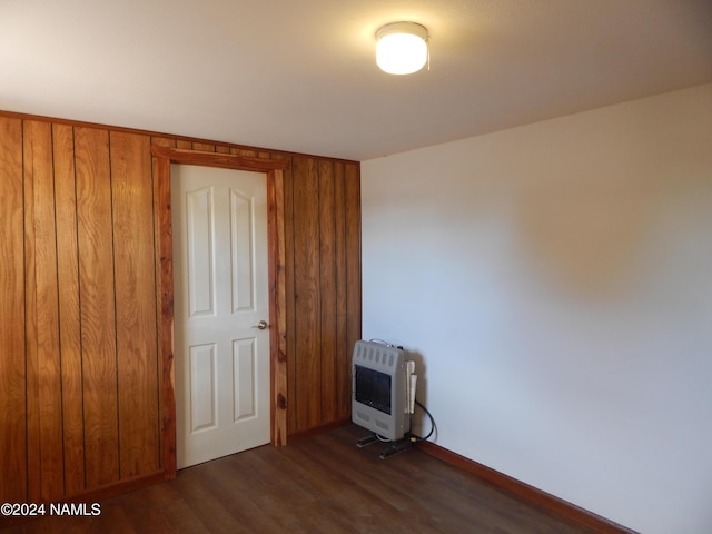 unfurnished bedroom featuring heating unit and dark hardwood / wood-style flooring