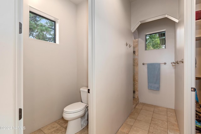 bathroom with a wealth of natural light, toilet, and tile patterned flooring