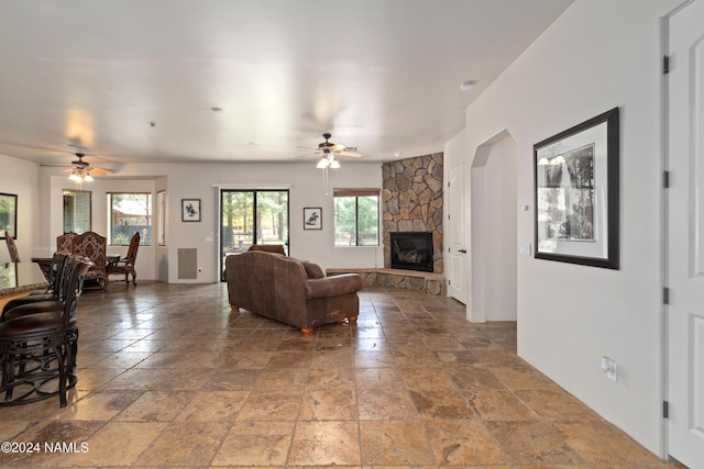 living room featuring ceiling fan and a fireplace