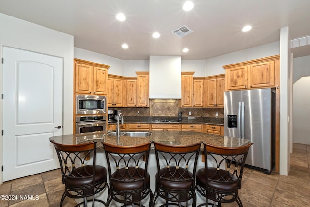 kitchen featuring sink, stainless steel appliances, a kitchen island with sink, and extractor fan