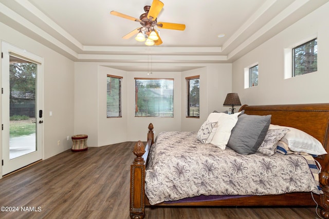 bedroom featuring ceiling fan, access to outside, dark wood-type flooring, and a tray ceiling