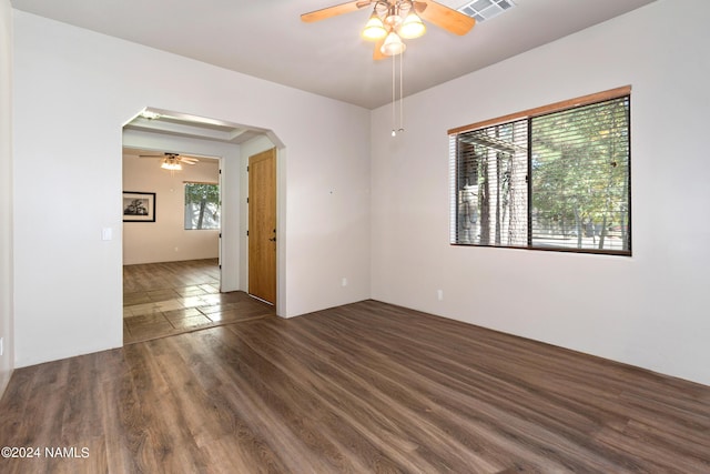 unfurnished room featuring ceiling fan, dark hardwood / wood-style flooring, and a healthy amount of sunlight