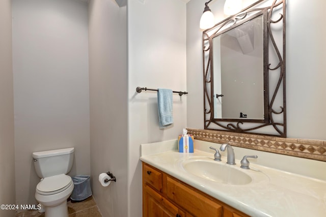 bathroom with toilet, vanity, and tile patterned flooring