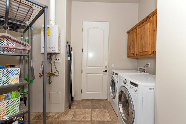 laundry room featuring washing machine and clothes dryer, cabinets, and water heater