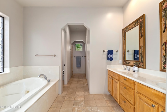 bathroom with tiled bath, tile patterned floors, and vanity