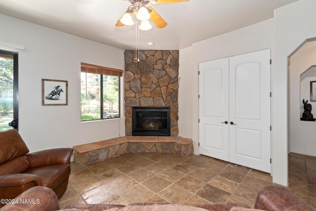 living room with ceiling fan and a stone fireplace