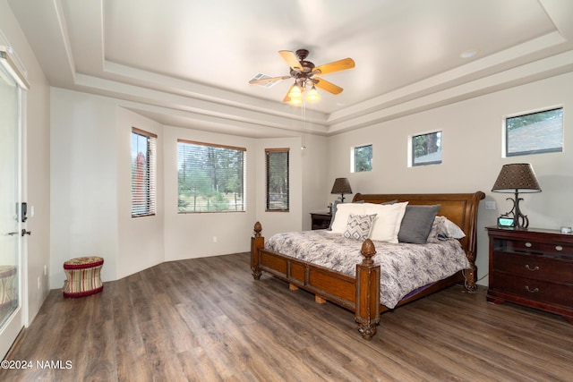 bedroom with ceiling fan, wood-type flooring, and a tray ceiling