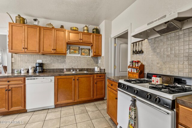 kitchen with white appliances, a textured ceiling, sink, backsplash, and light tile patterned flooring