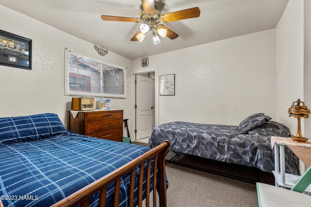 carpeted bedroom with ceiling fan and a textured ceiling