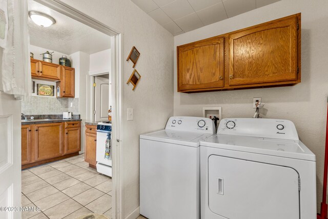 washroom featuring sink, cabinets, light tile patterned floors, and washing machine and clothes dryer