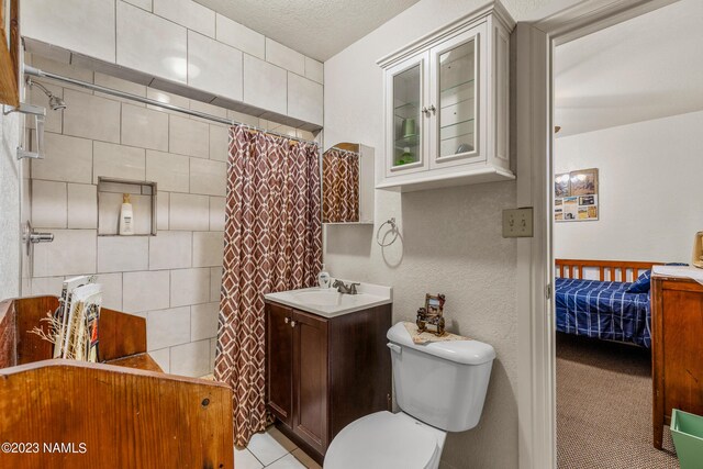 bathroom with toilet, a textured ceiling, walk in shower, tile patterned floors, and vanity