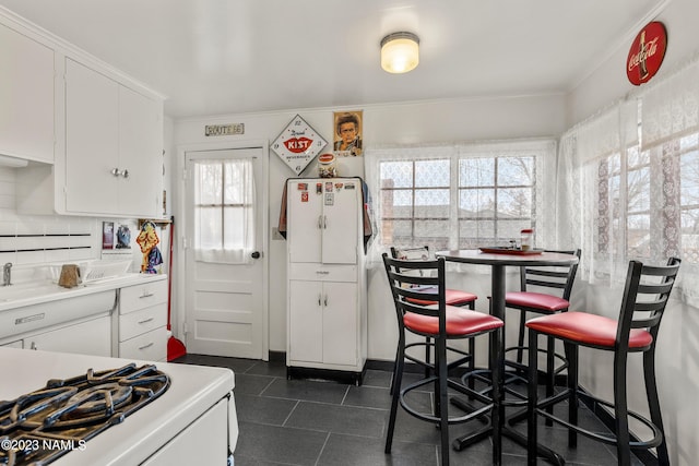 kitchen with stove, white cabinetry, and decorative backsplash