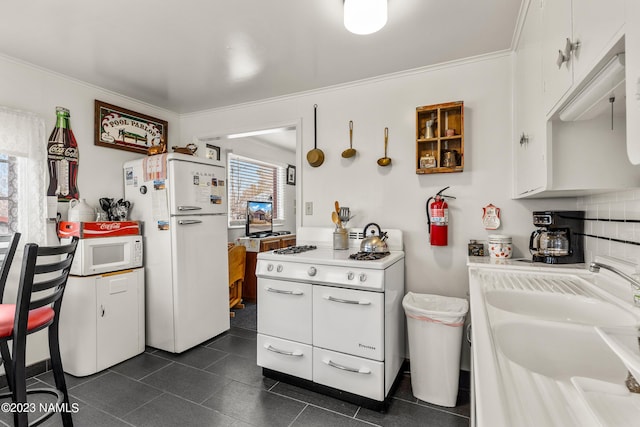 kitchen with white appliances, crown molding, white cabinetry, sink, and backsplash