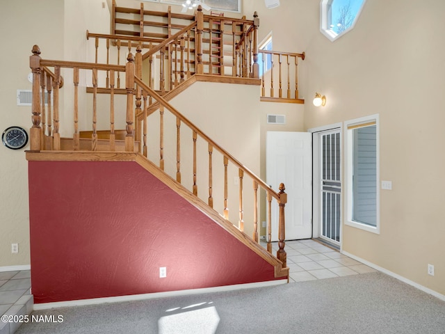 3792 E Ramble Wood Dr, Flagstaff, AZ 86004 - carpeted entrance foyer with visible vents, baseboards, stairs, a towering ceiling, and tile patterned floors