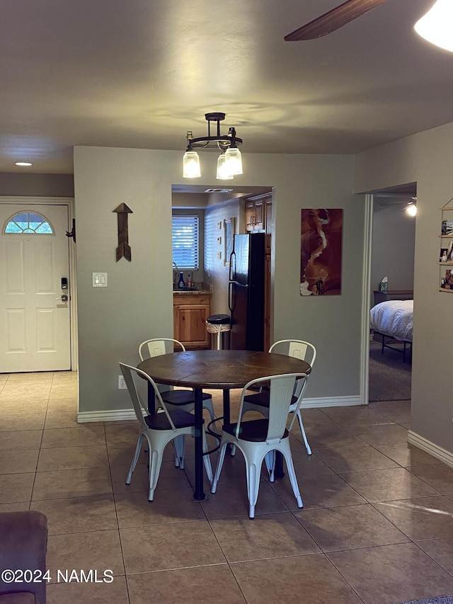 dining space featuring ceiling fan with notable chandelier, sink, and tile patterned floors