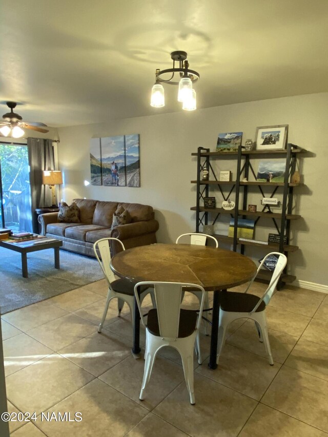 tiled dining room with ceiling fan with notable chandelier