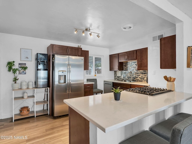 2821 N Tindle Blvd, Flagstaff, AZ 86004 - kitchen with appliances with stainless steel finishes, a sink, a peninsula, light wood-type flooring, and visible vents