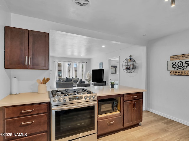2821 N Tindle Blvd, Flagstaff, AZ 86004 - kitchen featuring gas range, black microwave, light countertops, open floor plan, and light wood-style flooring