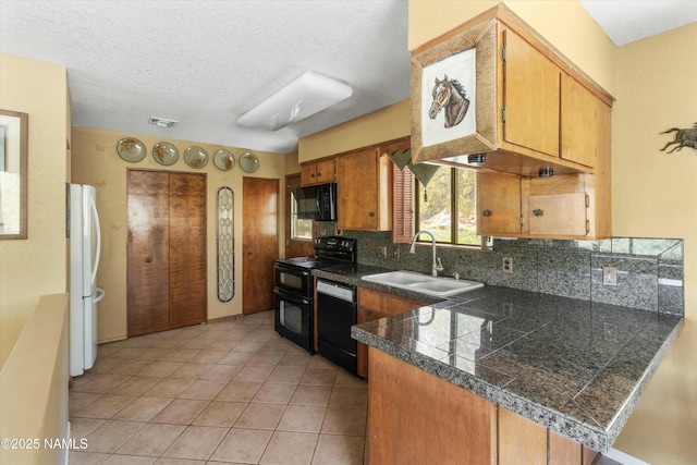 kitchen with a sink, tile counters, light tile patterned floors, tasteful backsplash, and black appliances