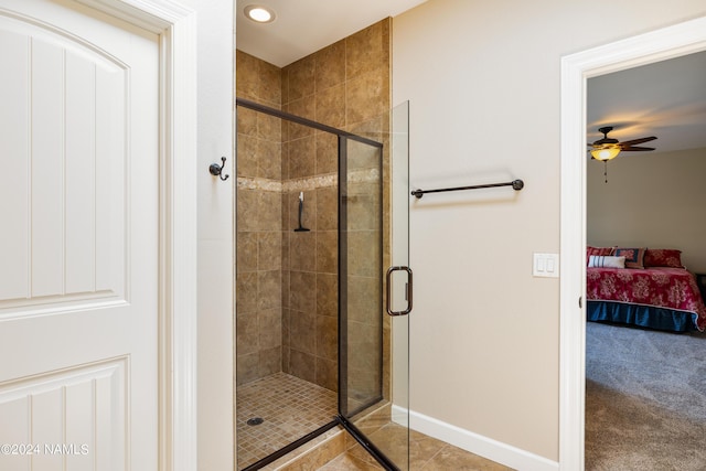 bathroom with tile patterned flooring, a shower with shower door, and ceiling fan