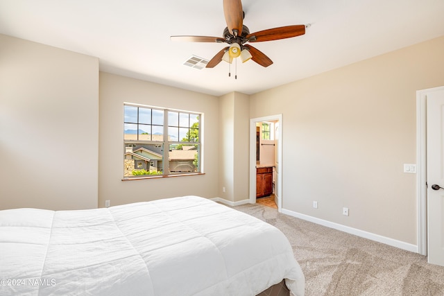 bedroom featuring ensuite bath, light colored carpet, and ceiling fan