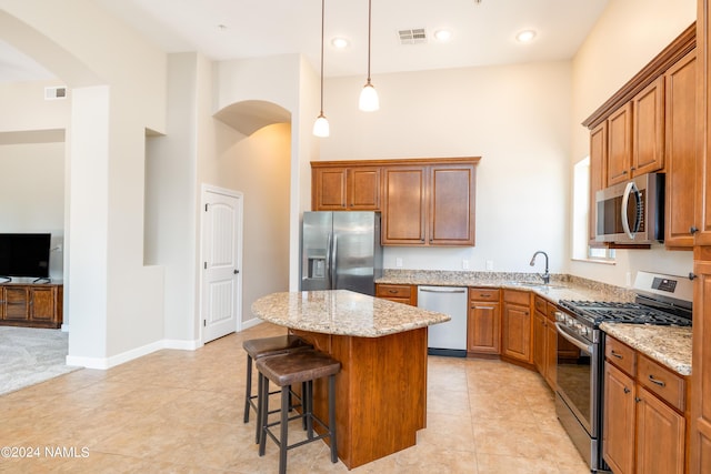 kitchen with a kitchen island, appliances with stainless steel finishes, a breakfast bar, a towering ceiling, and sink