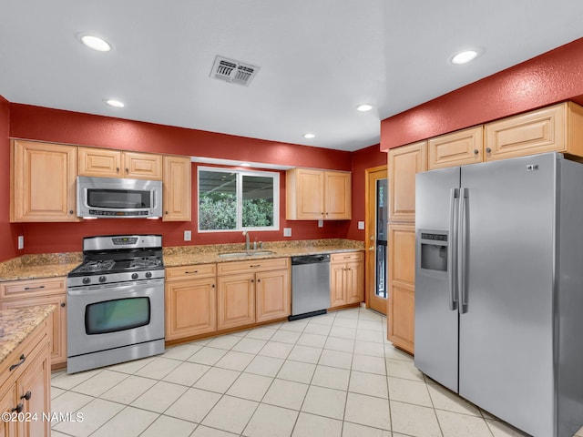 kitchen featuring light brown cabinetry, appliances with stainless steel finishes, sink, light tile patterned floors, and light stone countertops