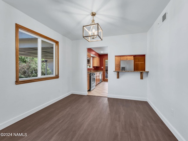 unfurnished living room with light wood-type flooring and an inviting chandelier