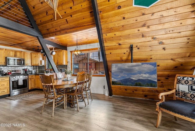 dining area featuring vaulted ceiling with beams, wood finished floors, and wooden ceiling