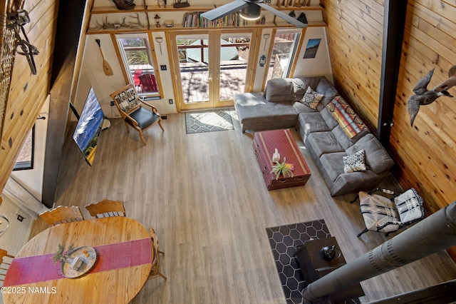 living room with french doors, a ceiling fan, wooden walls, and wood finished floors
