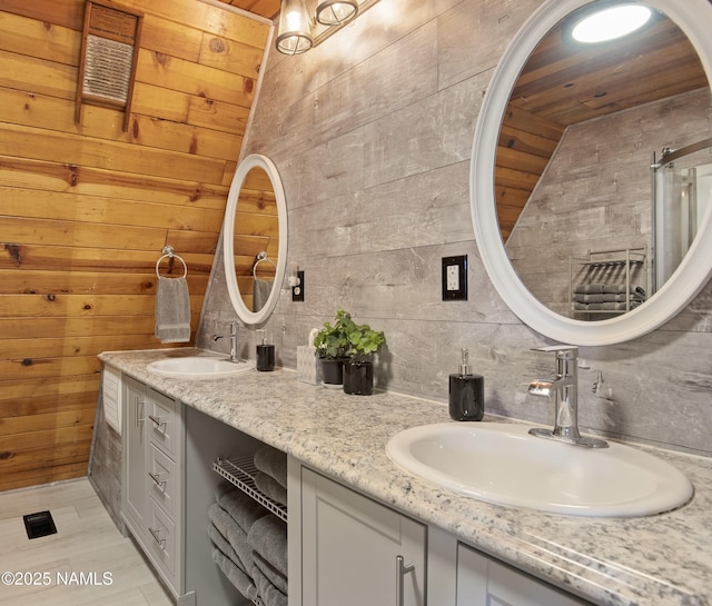 full bath with double vanity, a sink, backsplash, and wood walls