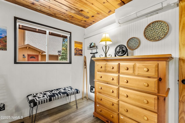 interior space with wood ceiling, baseboards, a wall mounted AC, and wood finished floors