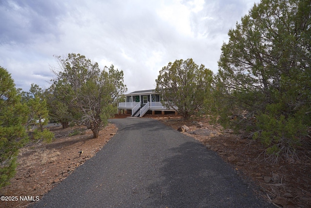 view of front of home featuring covered porch, driveway, and stairway