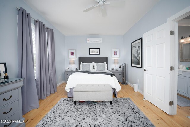 bedroom featuring an AC wall unit, baseboards, light wood-style floors, and a ceiling fan