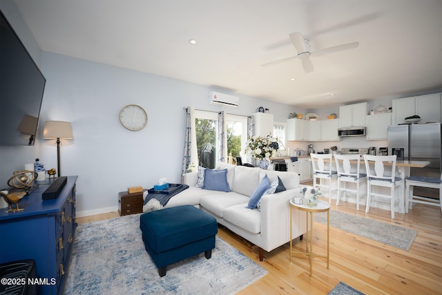 living area with light wood finished floors, a wall unit AC, recessed lighting, and a ceiling fan