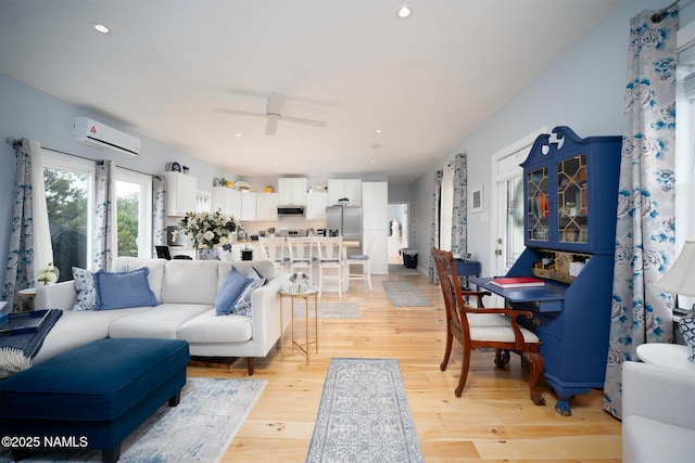 living area with a ceiling fan, an AC wall unit, light wood-style floors, and recessed lighting