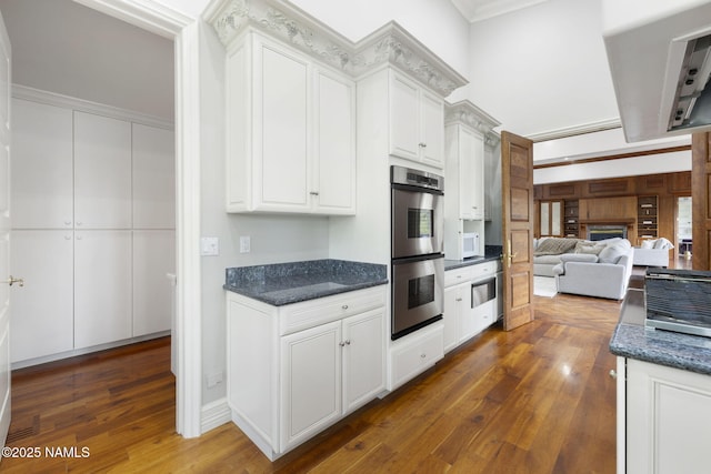 1430 E Puma Pl Unit F, Munds Park, AZ 86017 - kitchen with stainless steel double oven, dark wood-style floors, white cabinetry, crown molding, and dark stone countertops
