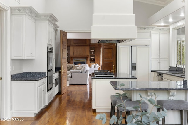 1430 E Puma Pl Unit F, Munds Park, AZ 86017 - kitchen with paneled refrigerator, a breakfast bar area, custom exhaust hood, dark wood finished floors, and a lit fireplace