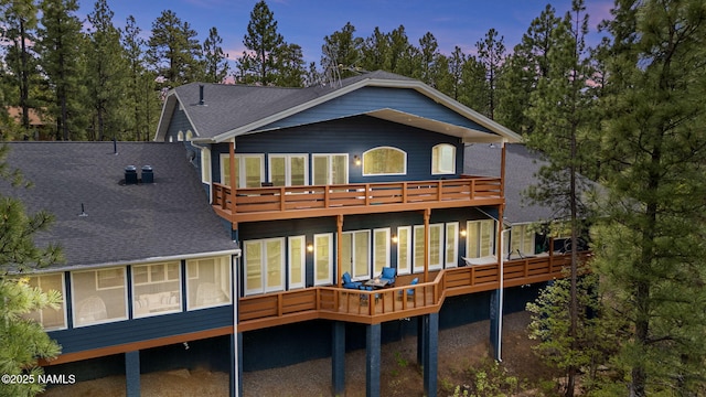 1430 E Puma Pl Unit F, Munds Park, AZ 86017 - back of property at dusk with a sunroom, a shingled roof, a balcony, and a wooden deck